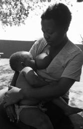 This is a black and white image, of a mother feeding her child in Braklaagte. This imaghe is also included in the Land Act Virtual exhibition.