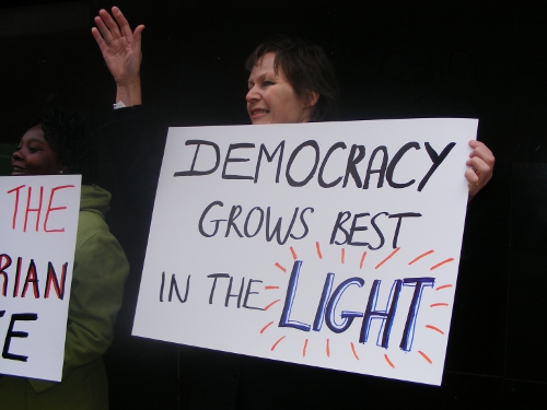 R2K protester holding plackard which reads 'Democracy grows in light